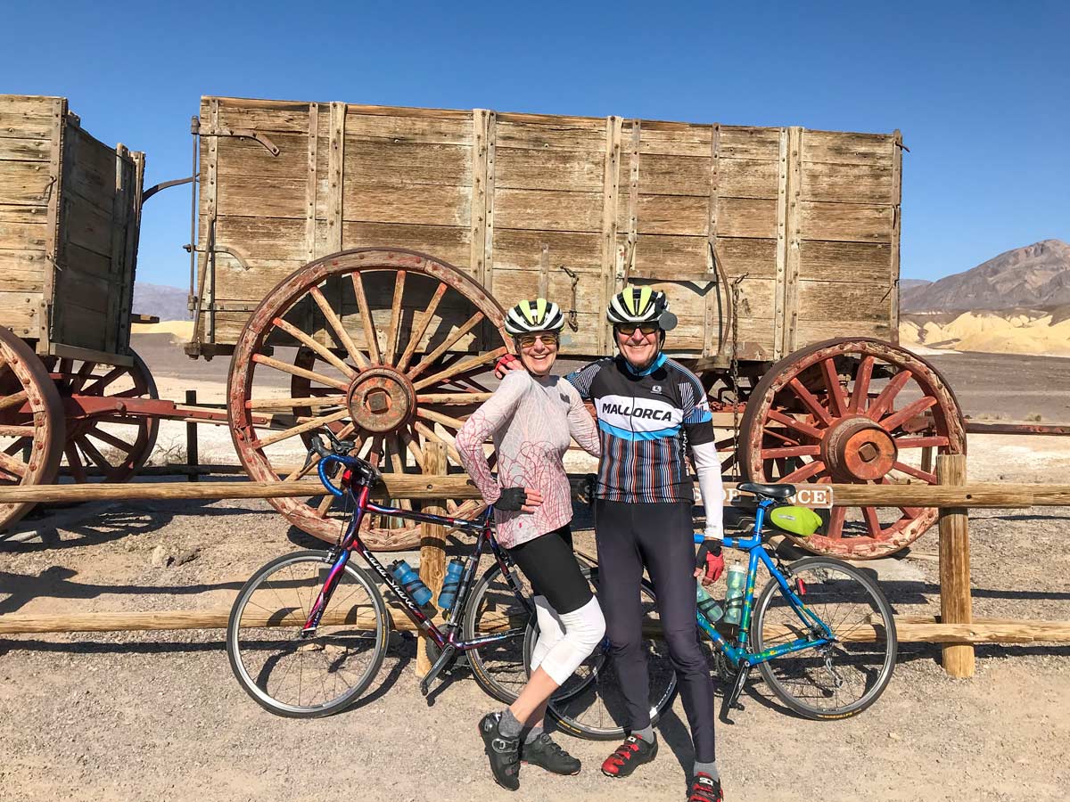 Cyclists pose by landmark exploring Death Valley National Park road biking tour