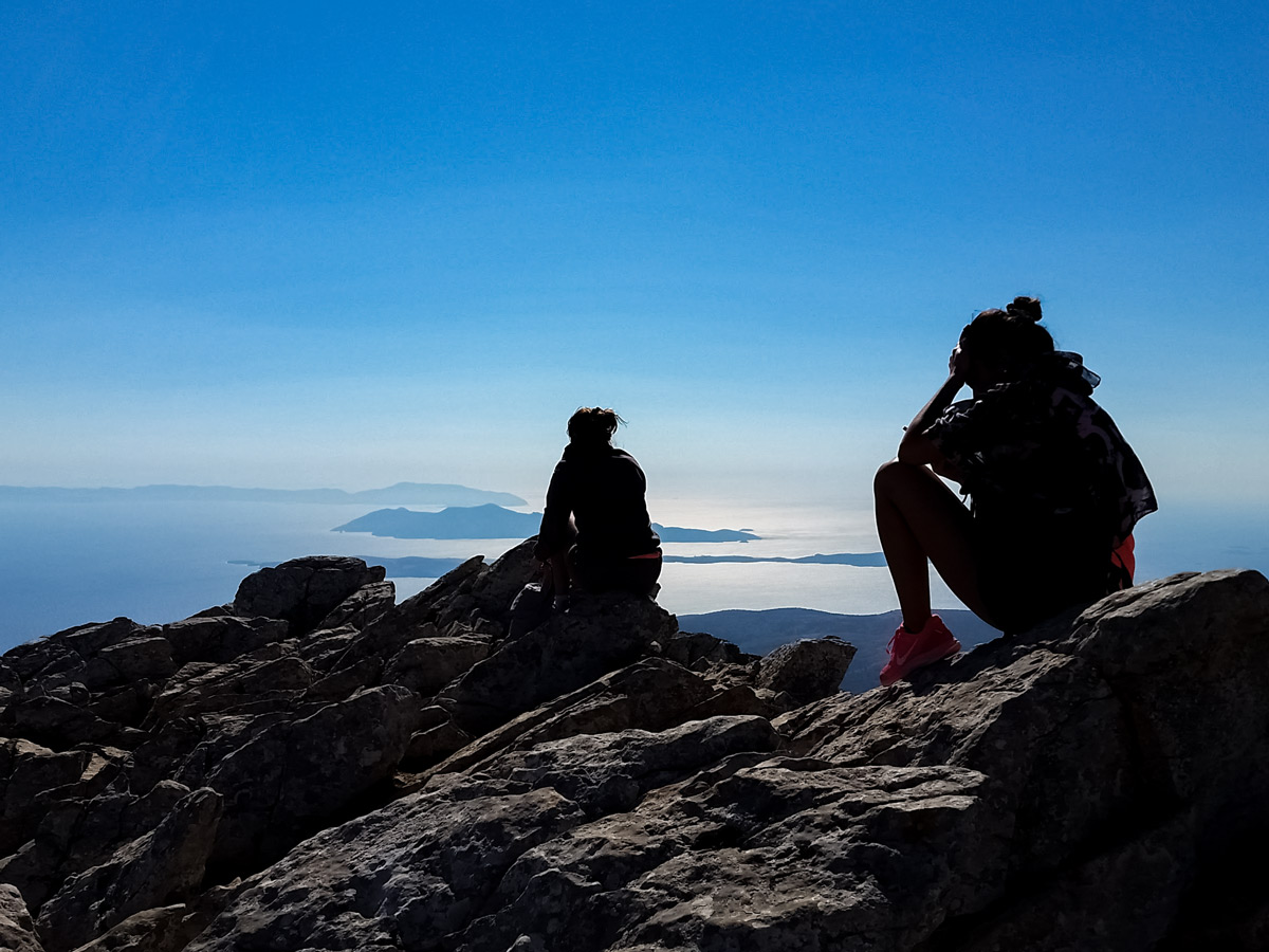 Hikers sitting high above mediterranean sea islands Naxos and Santorini Greece